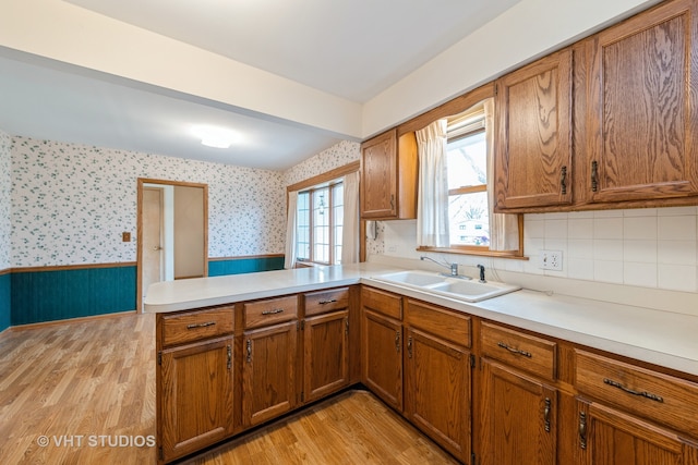 kitchen with light hardwood / wood-style floors, kitchen peninsula, and sink