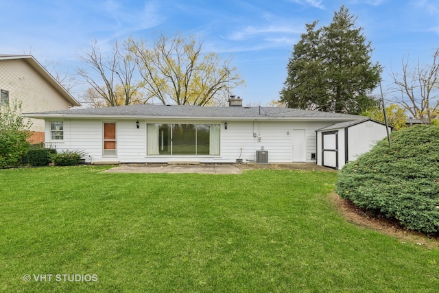 back of house with a lawn, cooling unit, and a storage unit