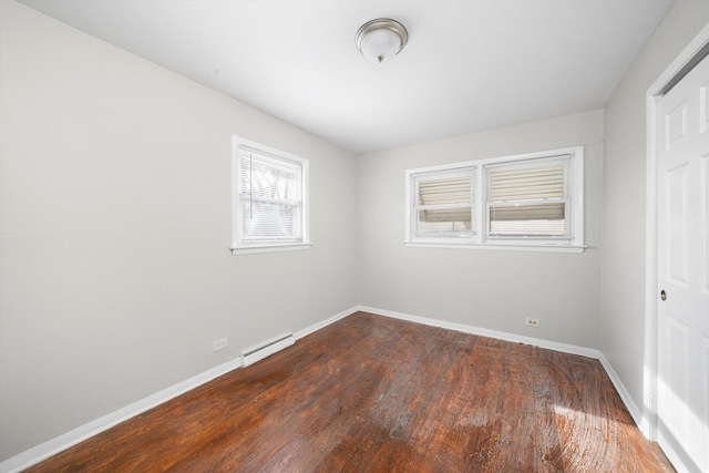 spare room with a baseboard radiator, baseboards, and wood finished floors