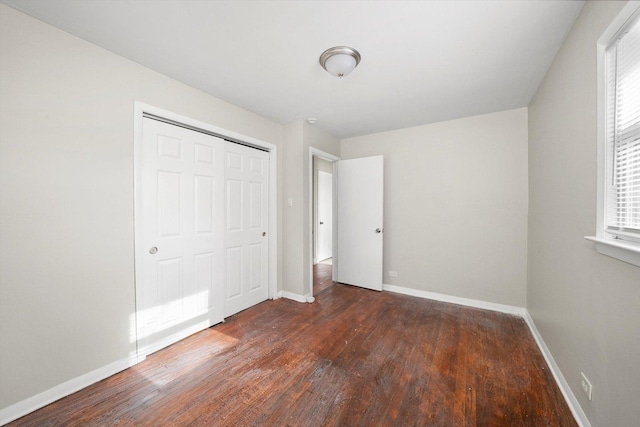 unfurnished bedroom with a closet, baseboards, and wood finished floors