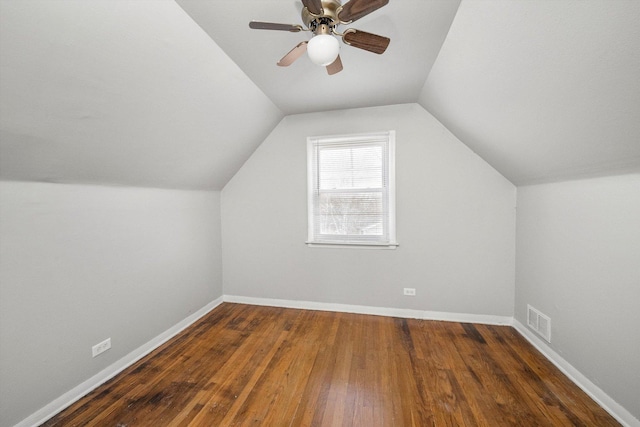 additional living space featuring lofted ceiling, wood finished floors, a ceiling fan, visible vents, and baseboards