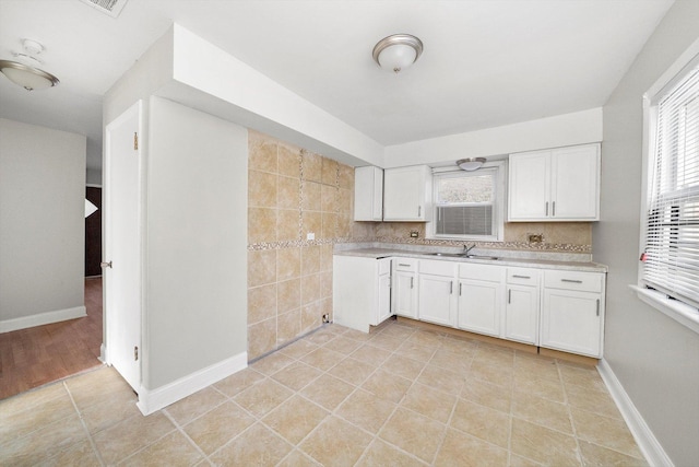 kitchen featuring light tile patterned floors, light countertops, a sink, and white cabinetry