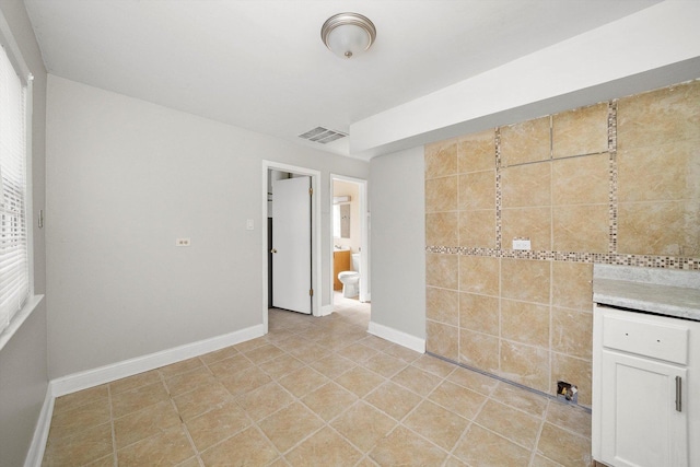 interior space featuring light tile patterned floors, baseboards, and visible vents