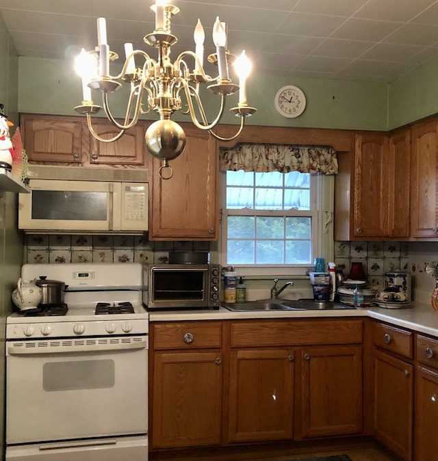 kitchen featuring decorative backsplash, white appliances, sink, and a chandelier