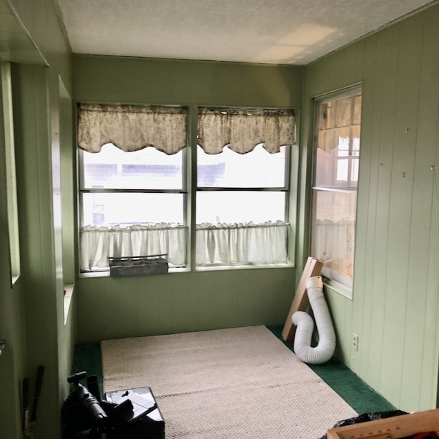 bedroom featuring wood walls, carpet, and a textured ceiling