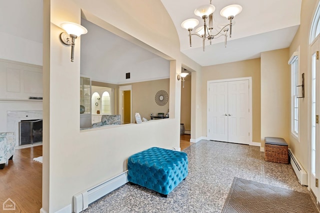 foyer entrance with hardwood / wood-style flooring, a notable chandelier, lofted ceiling, and a baseboard heating unit