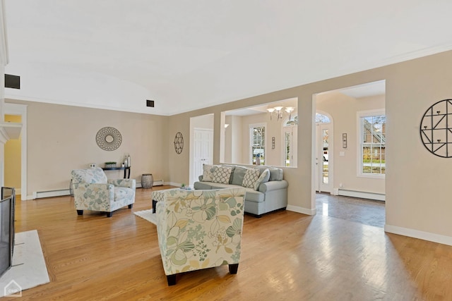 living room featuring baseboard heating, a notable chandelier, and light wood-type flooring