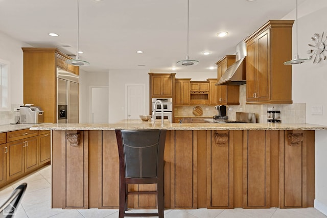 kitchen featuring pendant lighting, a kitchen breakfast bar, and wall chimney range hood