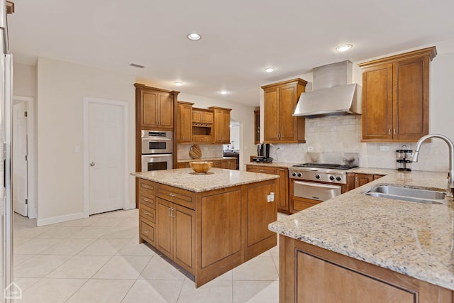 kitchen with sink, wall chimney range hood, tasteful backsplash, light stone counters, and double oven