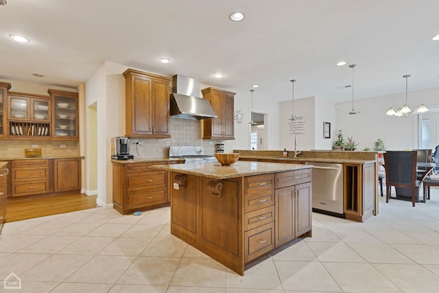 kitchen with kitchen peninsula, hanging light fixtures, stainless steel appliances, and wall chimney range hood