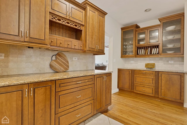 kitchen with backsplash, light hardwood / wood-style floors, and light stone counters