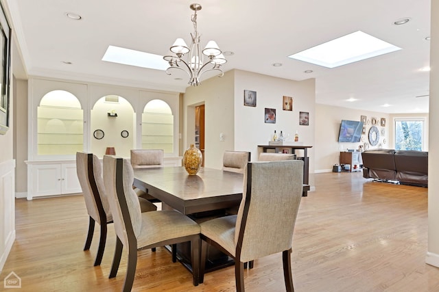 dining space featuring a skylight, light hardwood / wood-style flooring, and a chandelier