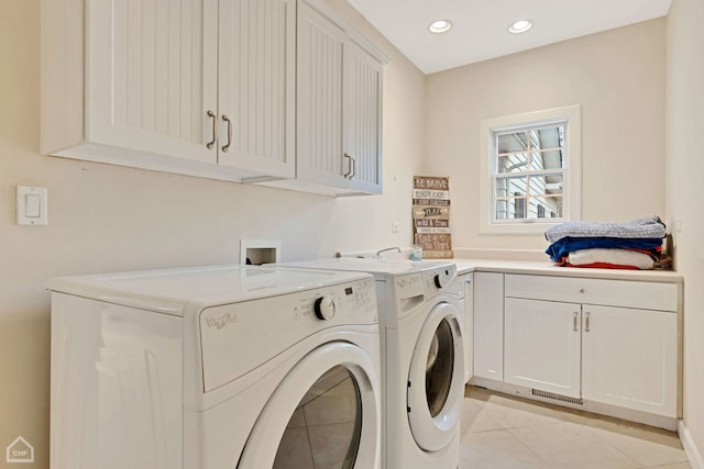 laundry area featuring washer and clothes dryer, cabinets, and light tile patterned floors