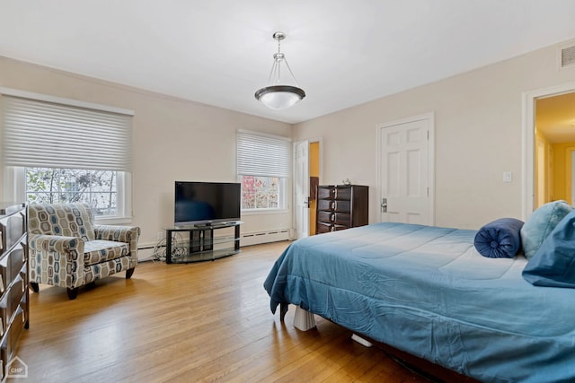 bedroom featuring baseboard heating and light hardwood / wood-style flooring