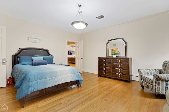 bedroom with light hardwood / wood-style floors and a baseboard heating unit