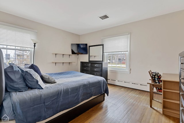 bedroom with baseboard heating and hardwood / wood-style floors