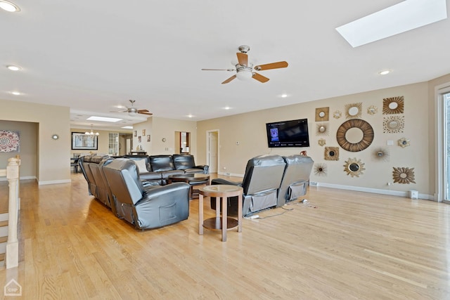 living room featuring a skylight, light hardwood / wood-style flooring, and ceiling fan