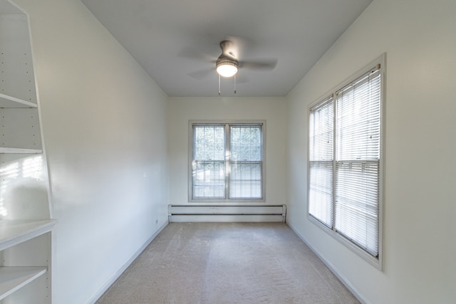 carpeted spare room featuring ceiling fan and a baseboard heating unit