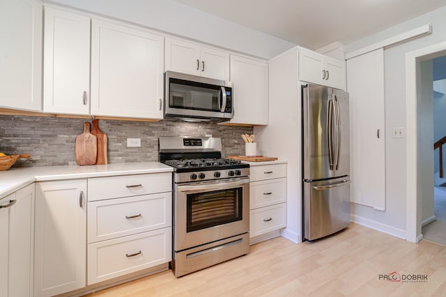 kitchen with stainless steel appliances, white cabinetry, tasteful backsplash, and light hardwood / wood-style floors