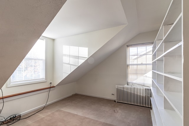 bonus room with radiator heating unit, carpet floors, and vaulted ceiling