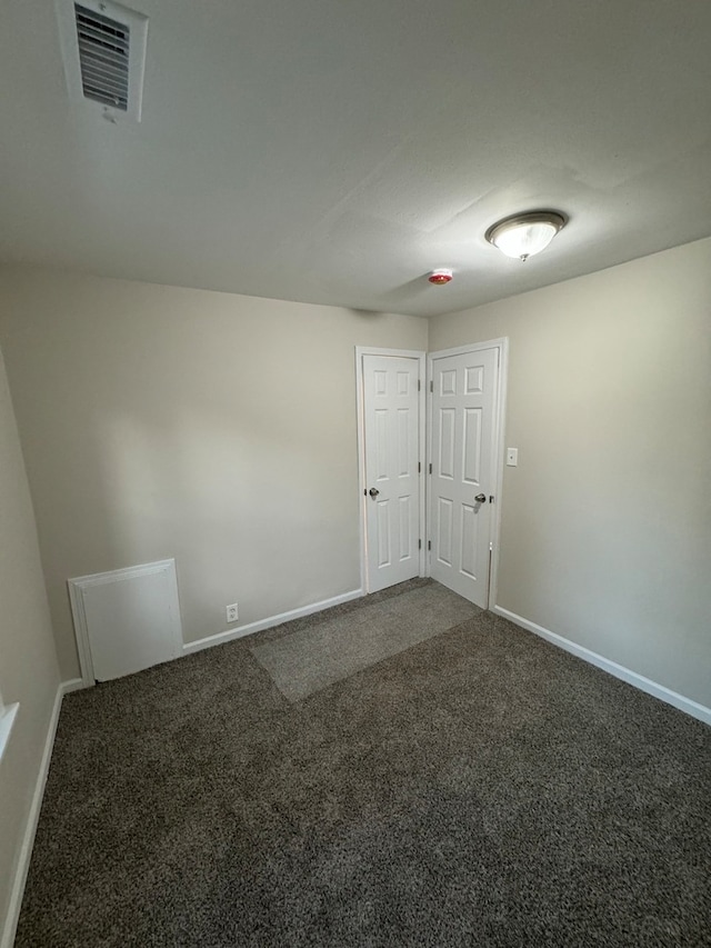 unfurnished room with dark colored carpet