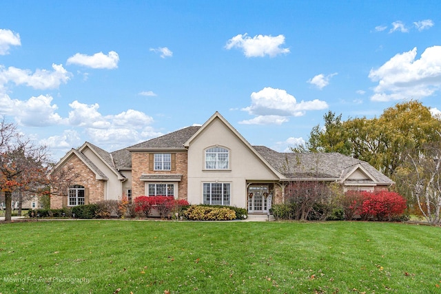 view of front of property with brick siding, a front yard, and stucco siding