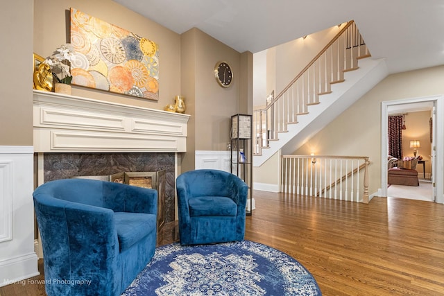 sitting room with wood finished floors, a fireplace, and stairs
