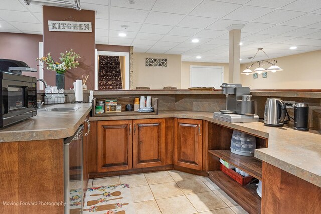 bar with stainless steel dishwasher, light tile patterned floors, a sink, black microwave, and pendant lighting