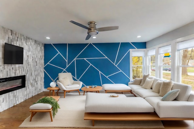 living room featuring ceiling fan, a fireplace, and wood-type flooring