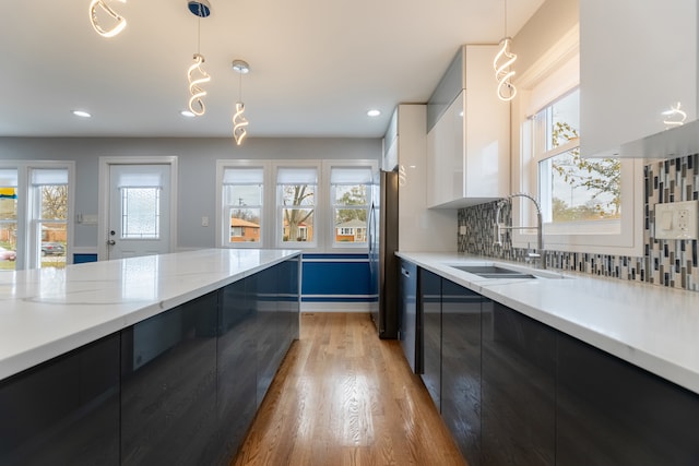 kitchen with white cabinets, sink, hanging light fixtures, and a wealth of natural light