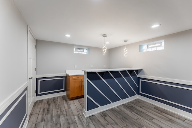 bar with a wealth of natural light, light hardwood / wood-style flooring, and hanging light fixtures