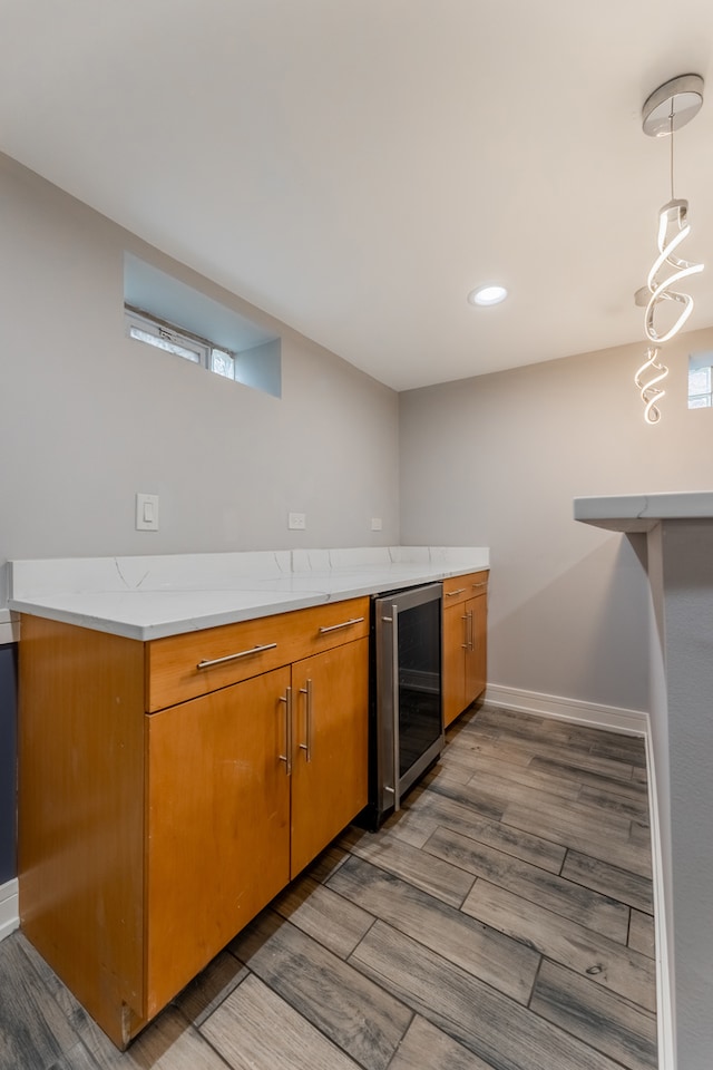 kitchen featuring hardwood / wood-style floors, wine cooler, hanging light fixtures, and light stone counters