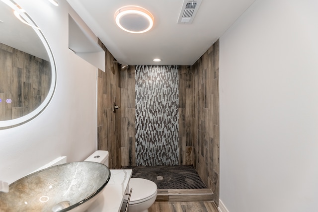 bathroom featuring a tile shower, vanity, and toilet