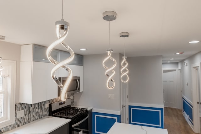 kitchen with pendant lighting, black gas stove, white cabinetry, and dark wood-type flooring