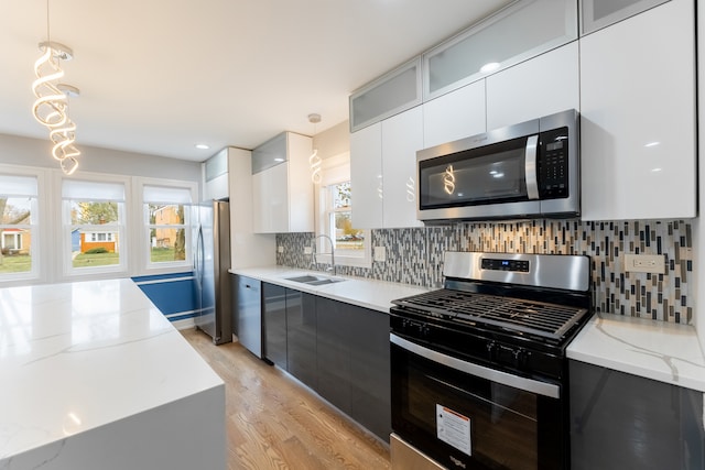 kitchen with decorative light fixtures, a healthy amount of sunlight, sink, and stainless steel appliances