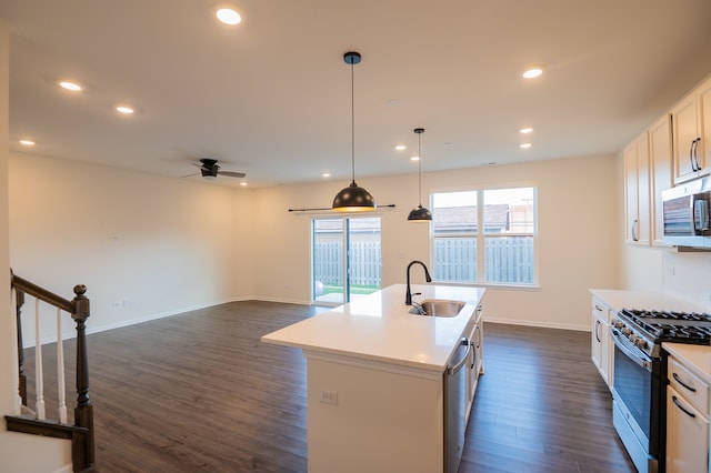 kitchen featuring dark wood-type flooring, a center island with sink, sink, appliances with stainless steel finishes, and white cabinetry