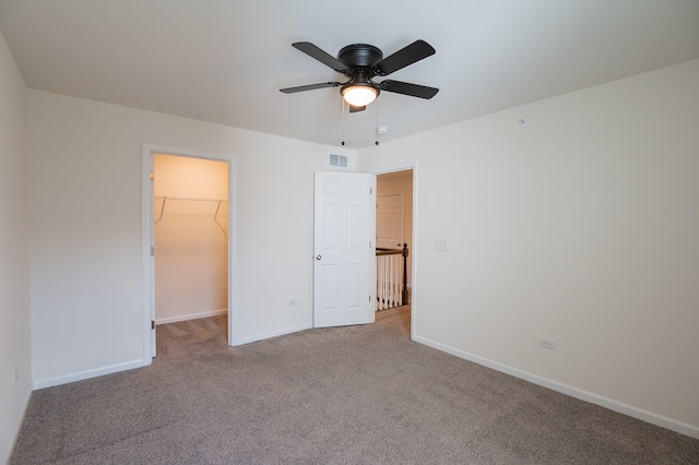 unfurnished bedroom featuring carpet flooring, ceiling fan, a walk in closet, and a closet