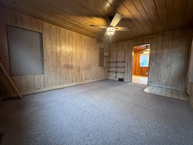 interior space featuring carpet flooring, wooden walls, ceiling fan, and wood ceiling