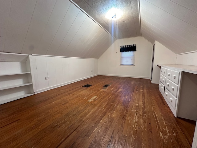 bonus room with dark hardwood / wood-style floors, built in features, and lofted ceiling