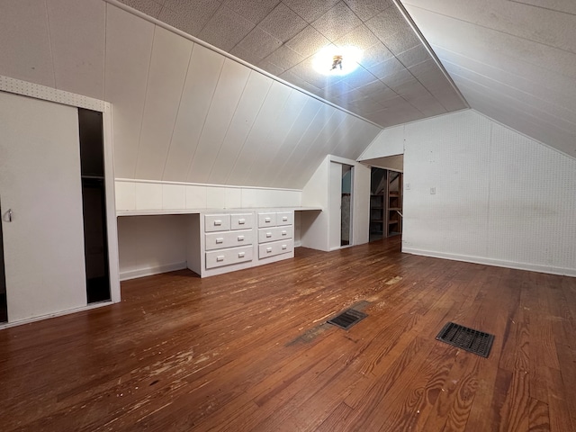 additional living space with hardwood / wood-style flooring and vaulted ceiling