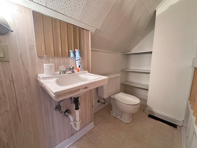 bathroom with toilet, sink, and vaulted ceiling