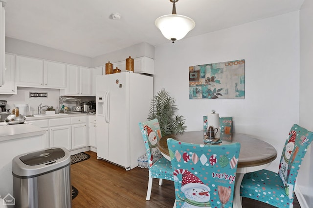 kitchen with white cabinetry, white fridge with ice dispenser, sink, hanging light fixtures, and dark wood-type flooring