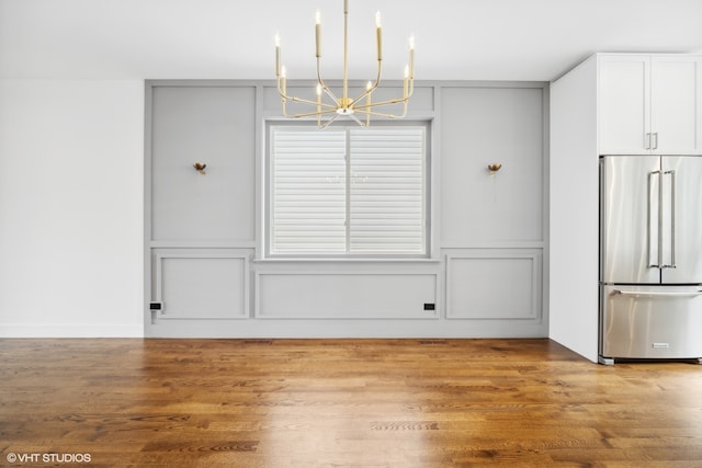 unfurnished dining area featuring light wood-type flooring and a chandelier