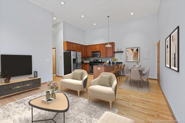 living room with light hardwood / wood-style flooring and a towering ceiling