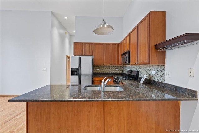 kitchen with kitchen peninsula, pendant lighting, stainless steel appliances, and dark stone countertops