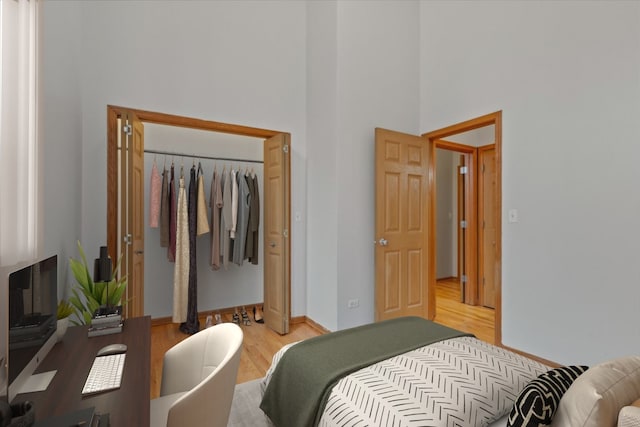 bedroom featuring light hardwood / wood-style floors, a high ceiling, and a closet