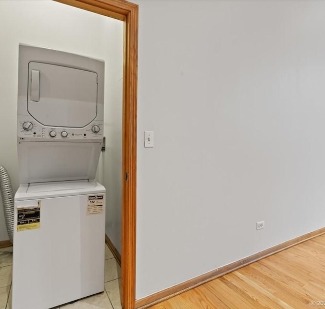 laundry room with light wood-type flooring and stacked washer / dryer