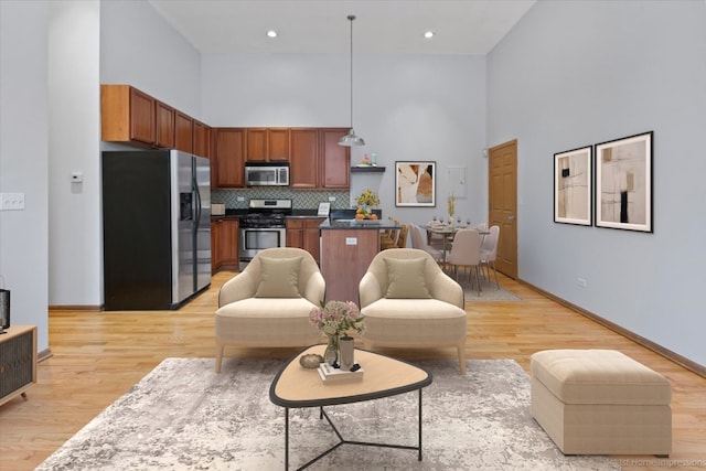 living room with a towering ceiling and light hardwood / wood-style flooring