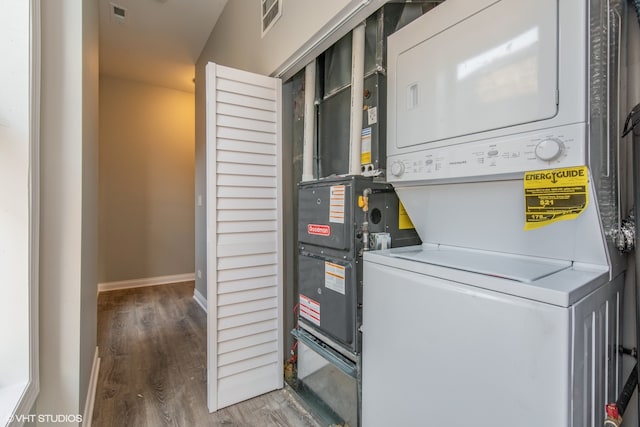 laundry room with wood-type flooring and stacked washer and dryer