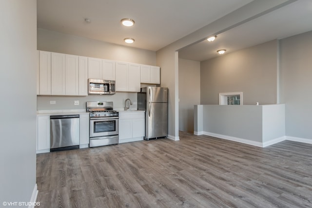 kitchen with sink, white cabinets, stainless steel appliances, and light wood-type flooring